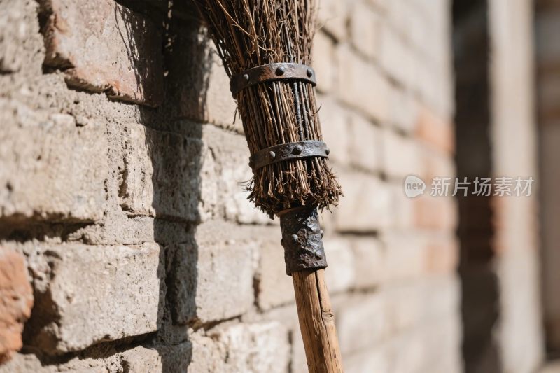 扫帚靠在砖墙