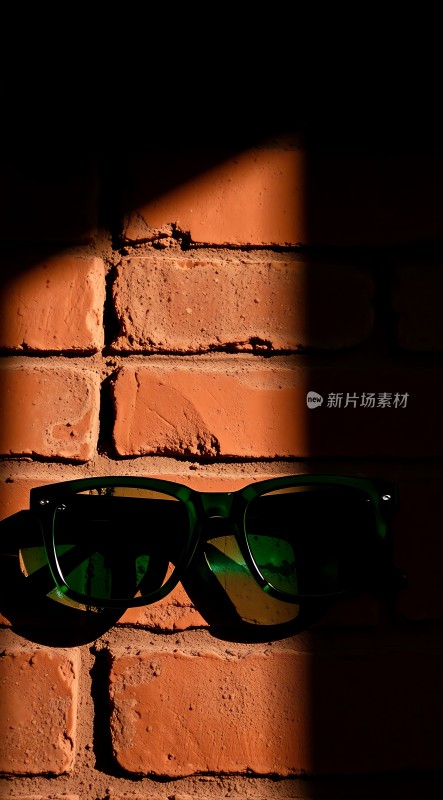 阳光下的墨镜与红砖墙