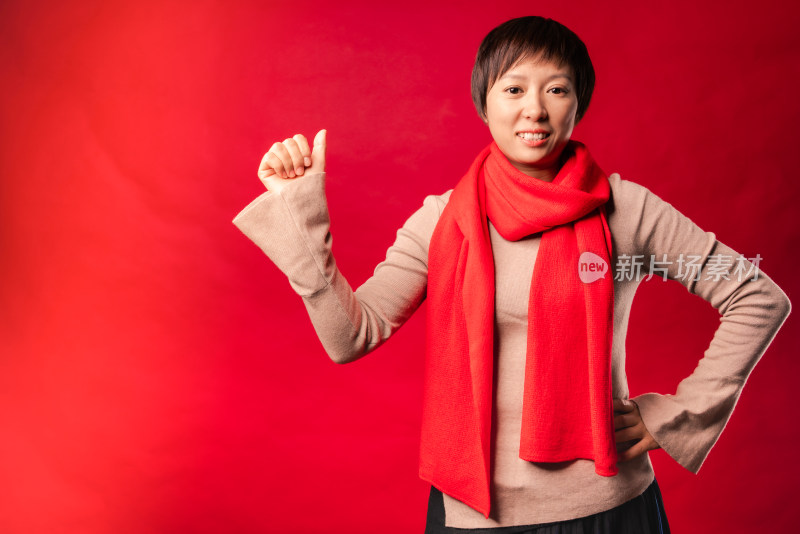 站在红色背景前竖大拇指的中国年轻女性