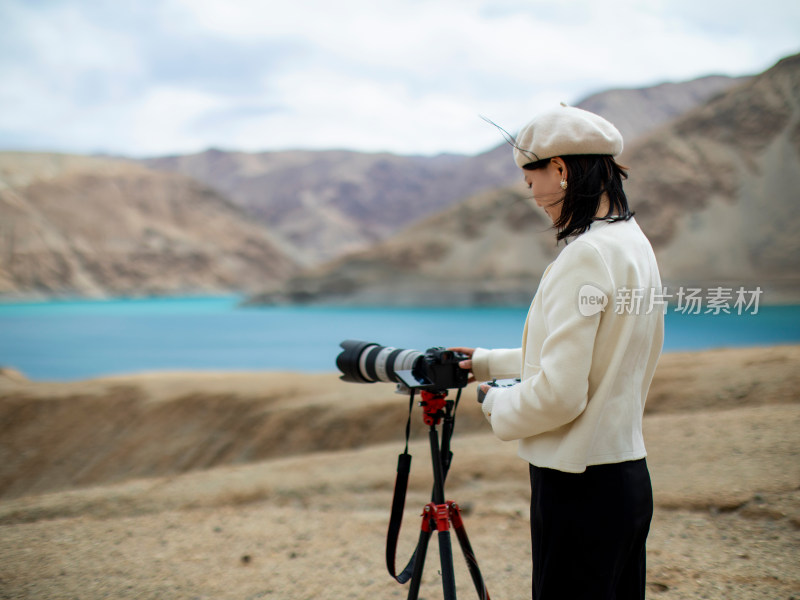 站在湖边操控相机的年轻女子摄影师
