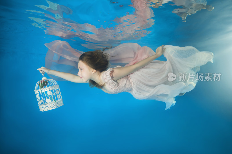 女孩水下持鸟笼身着纱裙漂浮
