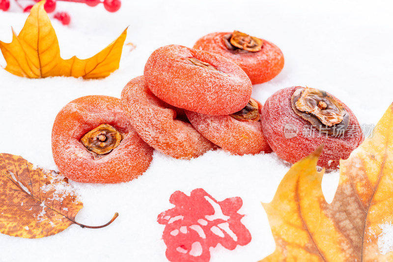 雪地上摆放的柿饼和秋叶