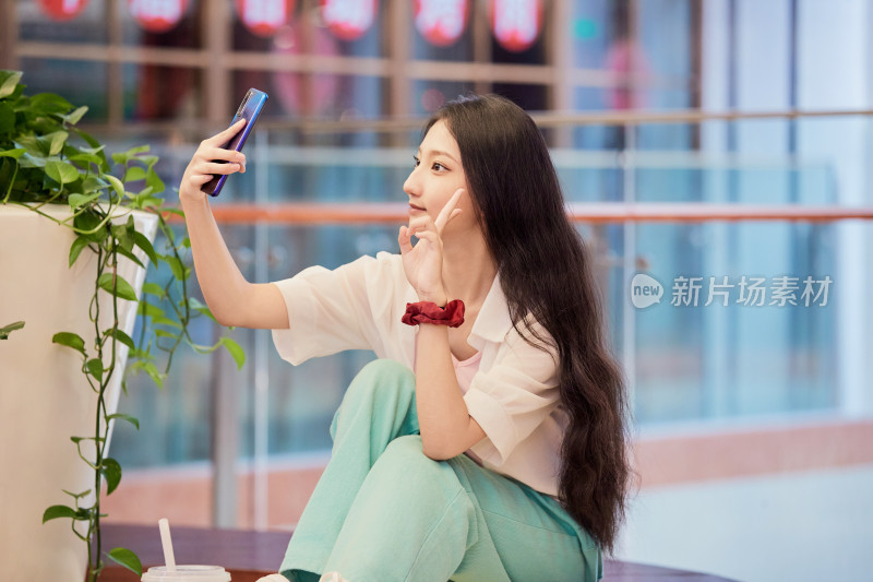 假日在商场休息区用手机自拍的中国少女