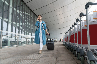 老年女人在机场拉着行李箱打电话