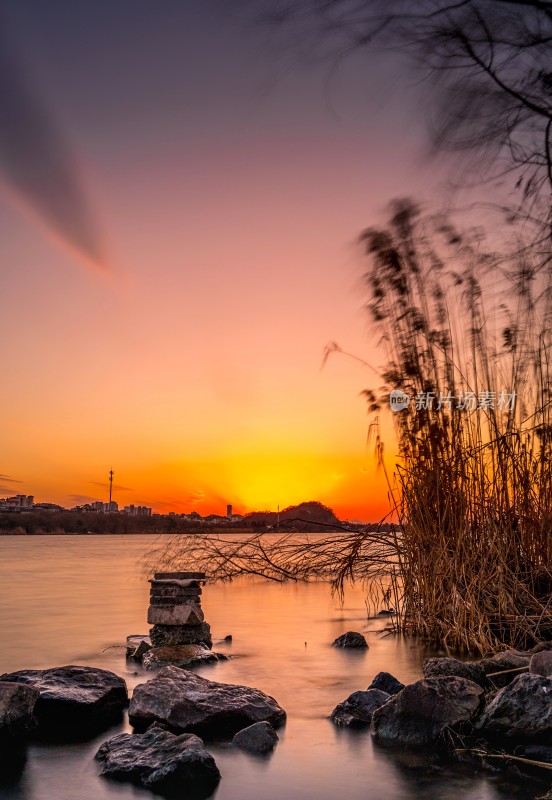 湖边日落景象，芦苇岩石相伴