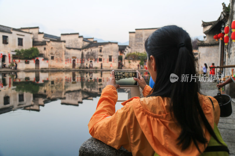 美丽女人用手机拍摄宏村月沼背影