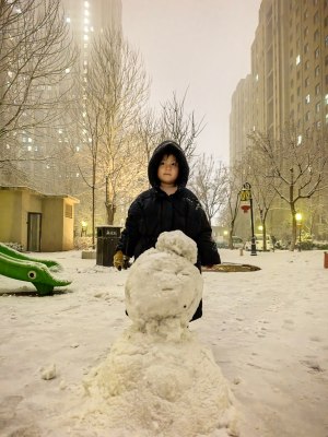 小孩雪天在户外与雪人合影