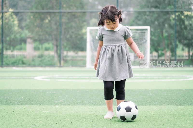 在足球场踢足球的中国女童