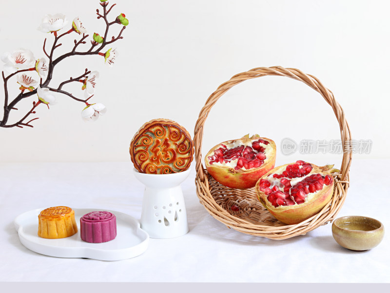 白色桌面上的中秋节月饼、茶和水果石榴