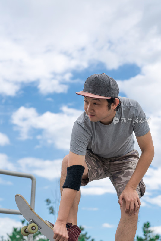 夏天在公园玩滑板的亚洲男性