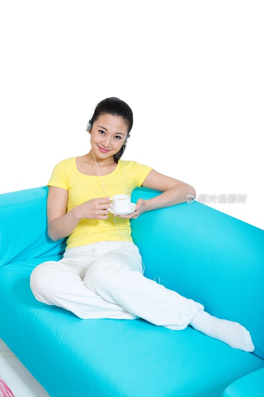 棚拍年轻女人坐在沙发上听着音乐喝咖啡