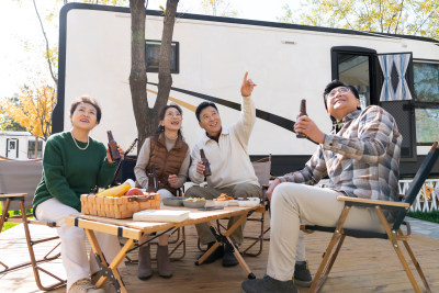 一群中老年人坐在房车露营地喝啤酒聊天