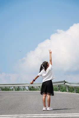 晴朗的夏天午后走在盘山公路上的东方女孩