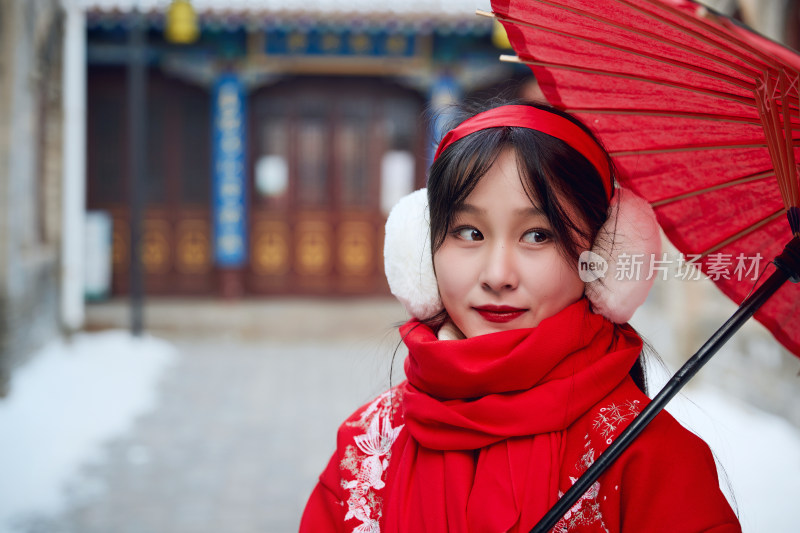 雪后在老城古巷穿着喜庆服饰的亚洲少女