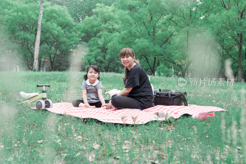 坐在公园草坪上玩耍的中国母女