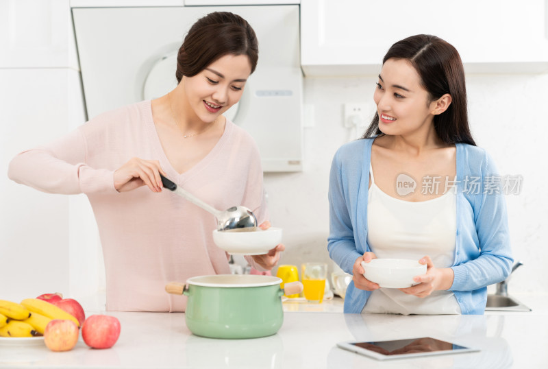 年轻女子在厨房边做饭边和朋友聊天