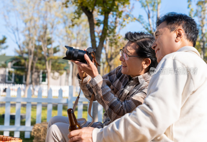 两个老年男人坐在露营地看数码相机