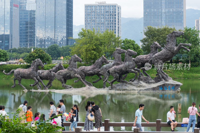 城市湖边群马雕塑与休闲人群