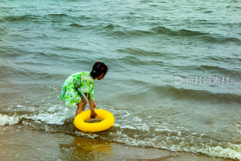 小女孩在南戴河海滨浴场拿着游泳圈下水游玩