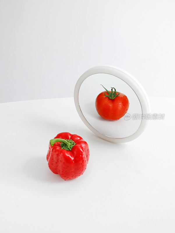 桌面上一个青椒和镜子中的一个番茄西红柿