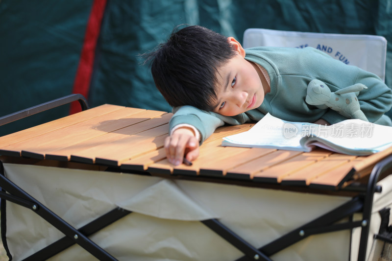 可爱的男孩在露营帐篷外写作业