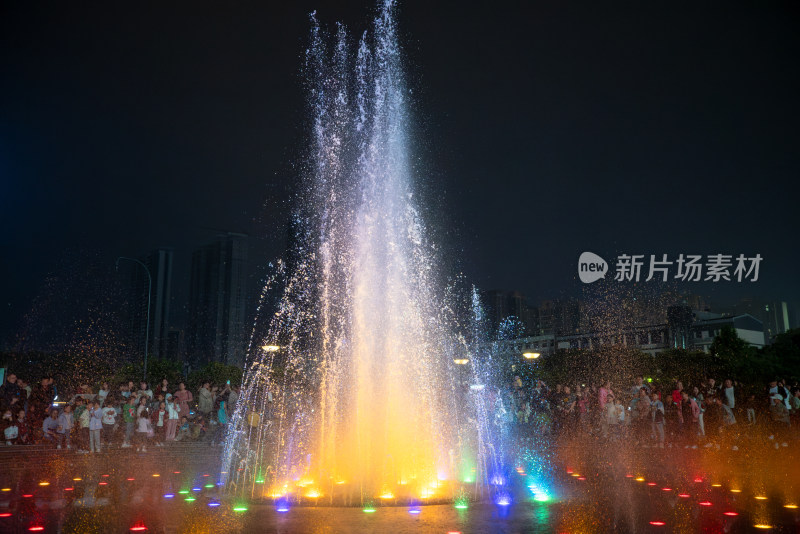 人群聚集处多彩喷泉绽放的夜景