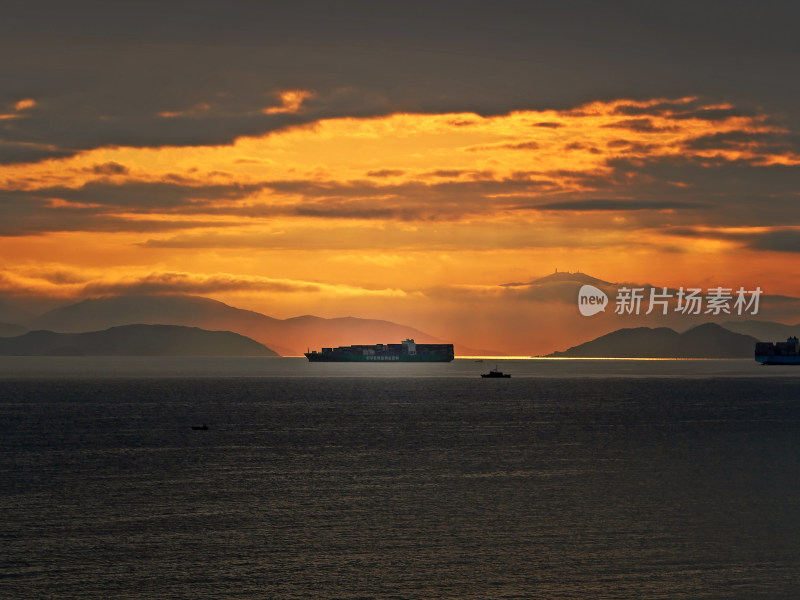 海上日出时的货轮与山峦美景