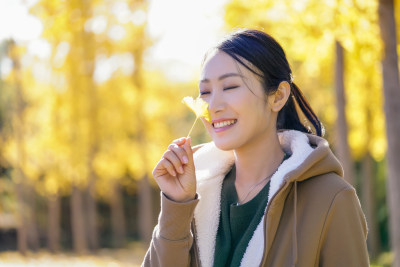 快乐的年轻女子手拿银杏叶