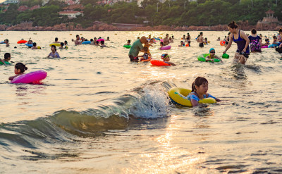 青岛汇泉湾夕阳下，海水浴场中的人们