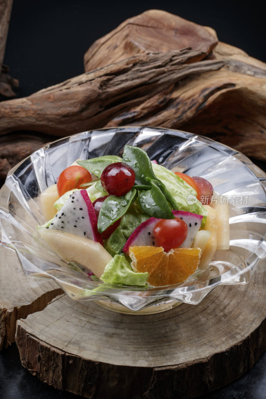 花纹玻璃碗装的果蔬拌菜摆放在樟木砧板上