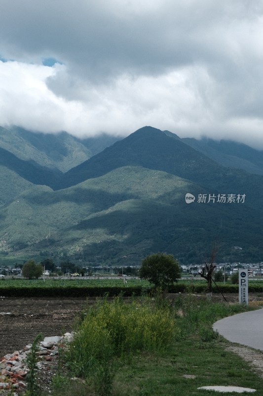 阴云下的青山远景及山脚下的土地