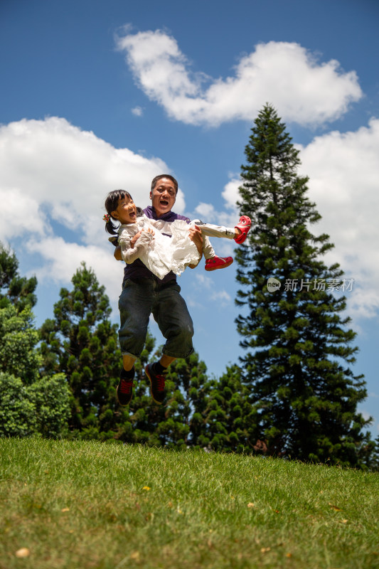 父亲抱着女儿户外欢乐跳跃
