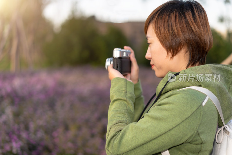 站在花丛中摄影的中国籍女性背影