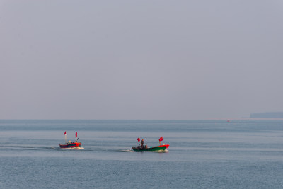 海上行驶着两艘插有红旗的小船