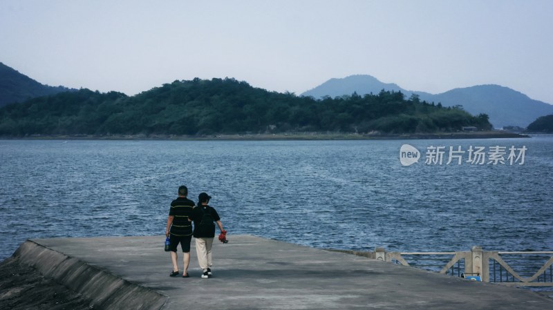 两人在水边步道漫步的惬意场景