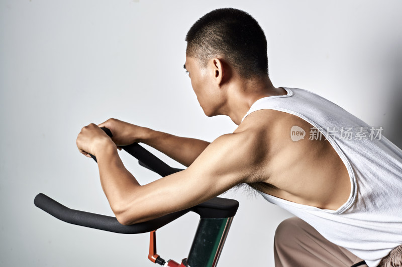 在室内进行动感单车锻炼的亚洲健身男士形象