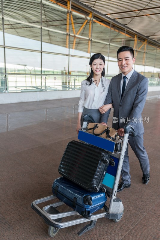 年轻情侣推着行李箱在机场走