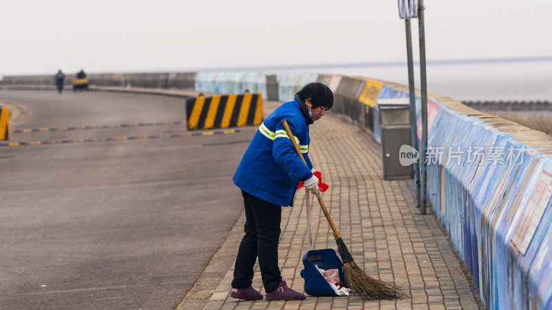 身穿工作服的环卫工人清扫人行道