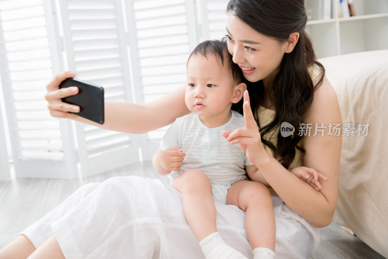 年轻妈妈用手机给宝宝照相