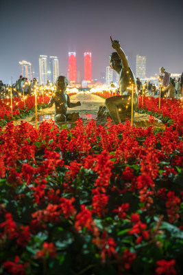 城市夜景下花丛中的人物雕像