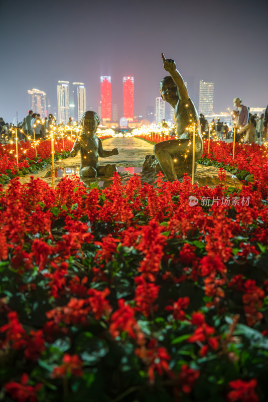 城市夜景下花丛中的人物雕像