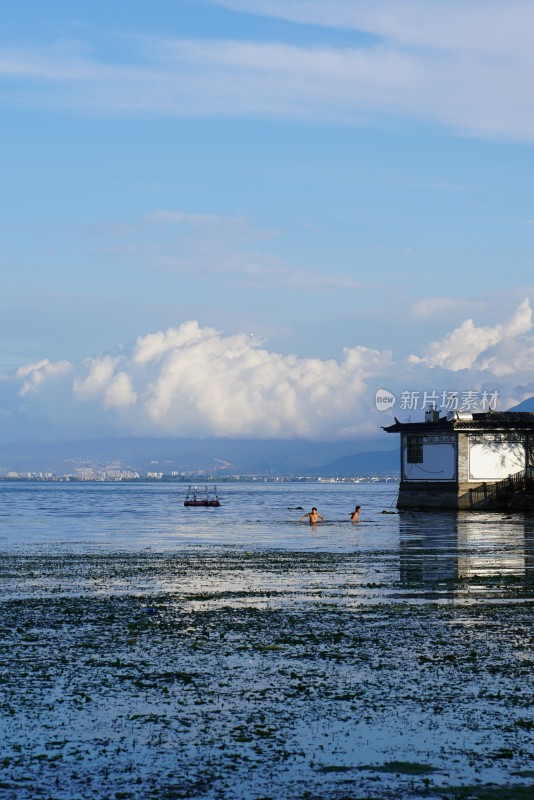 湖边人物戏水与湖景建筑