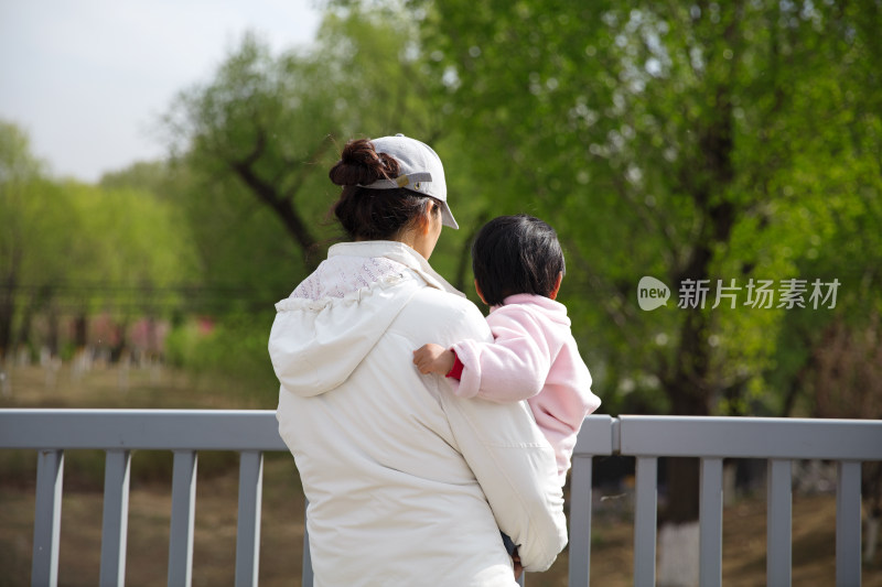 站在桥头抱着孩子的年轻妈妈