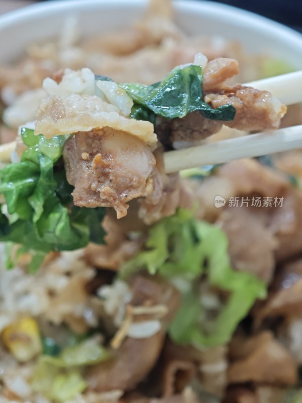 筷子夹起的肉片米饭