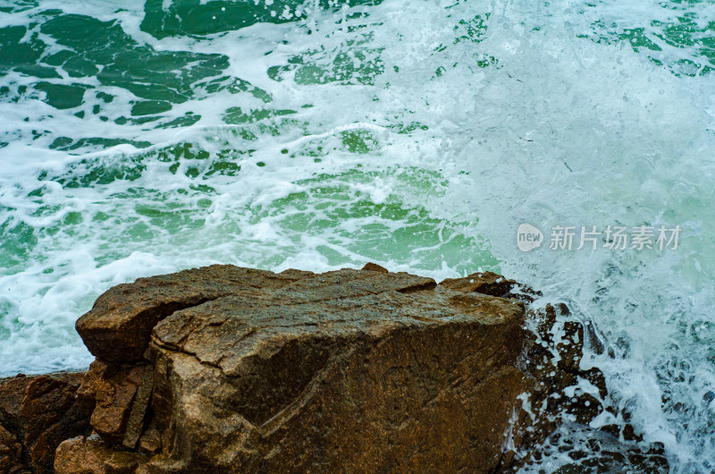 飞溅的浪花拍打在岩石上，瞬间特写