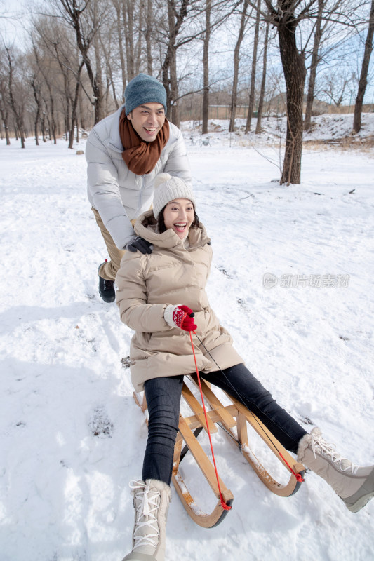 青年夫妇在雪地上玩雪橇