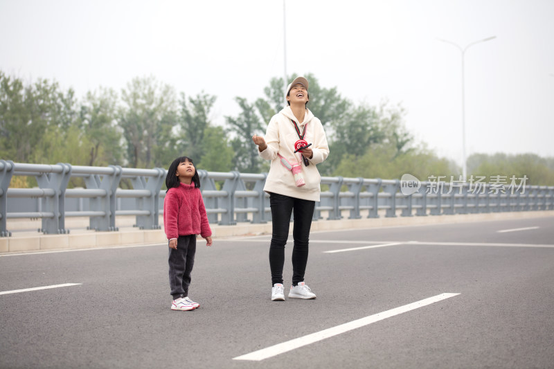 年轻妈妈在教孩子如何放风筝