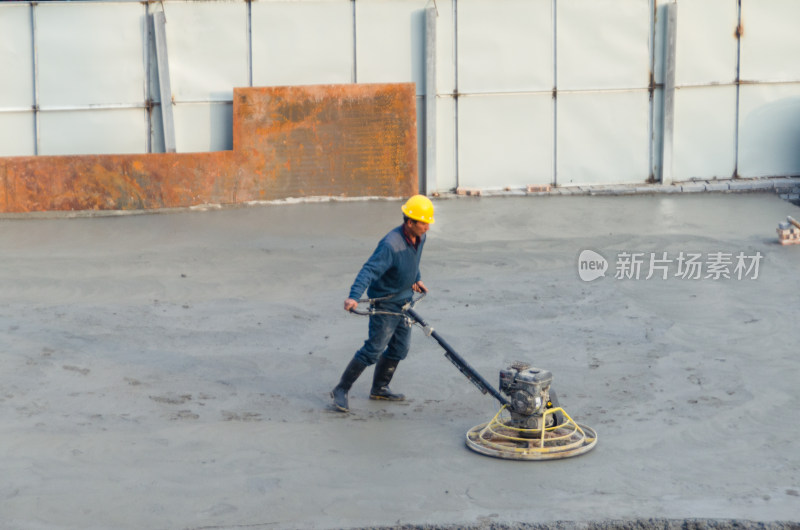 建筑工地上，工人使用路面抹平机平整路面