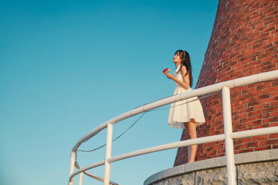 盛夏夕阳湖边码头灯塔上吃西瓜的少女