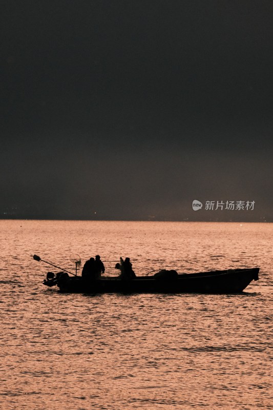 夕阳下海上渔船与人物剪影